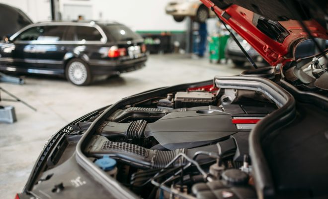 Car with opened hood in automobile service