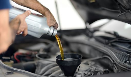 Man auto mechanic repairs car in autoservice, station. Changes oil.